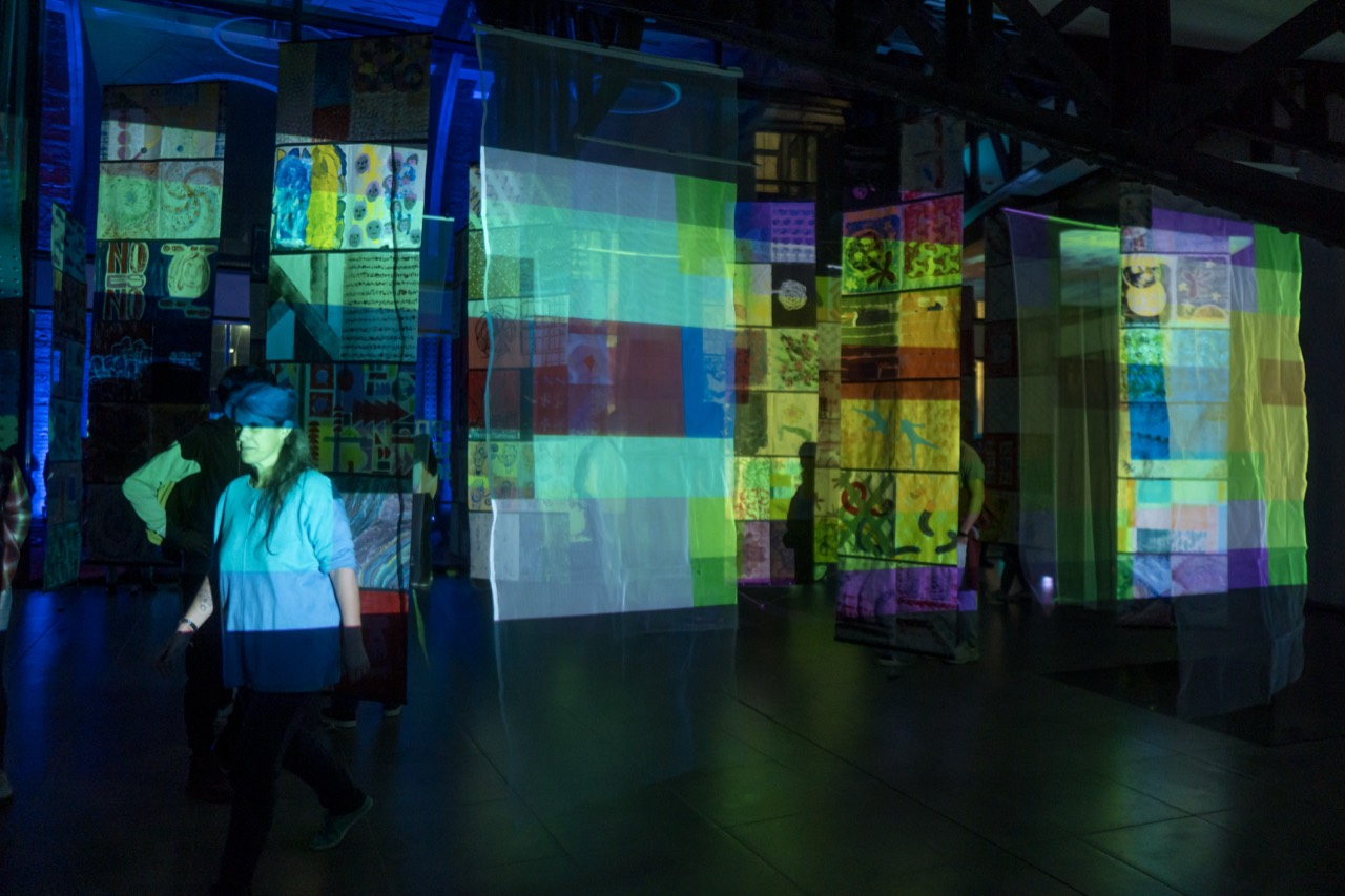 Lanzamiento interactivo — proyección de color sobre las columnas de hierro.