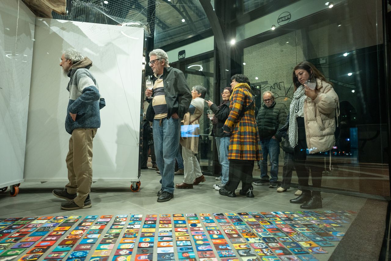 Gente en Obra — piso de pequeñas piezas de color, con público en el vernissage.