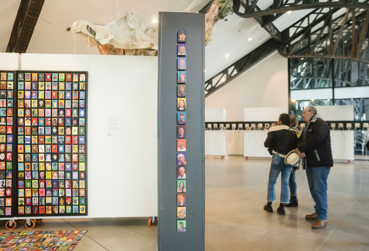 Gente en Obra — los paneles de retratos y una columna de retratos, con visitantes.